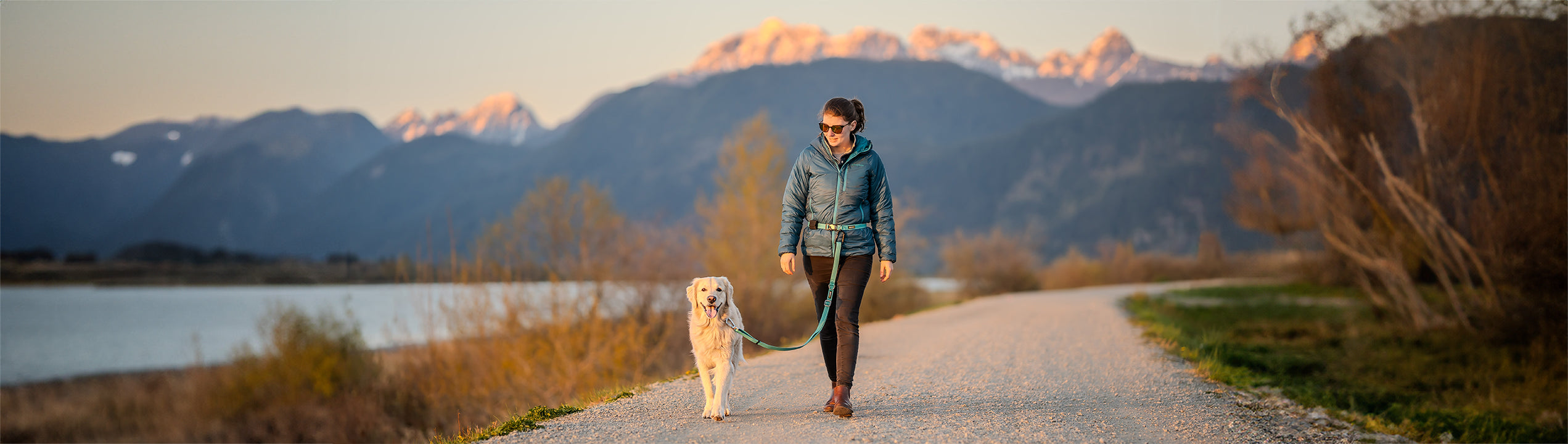 A woman walking a happy dog hands-free with a DogGo Collar, Leash and Belt in glacier teal.